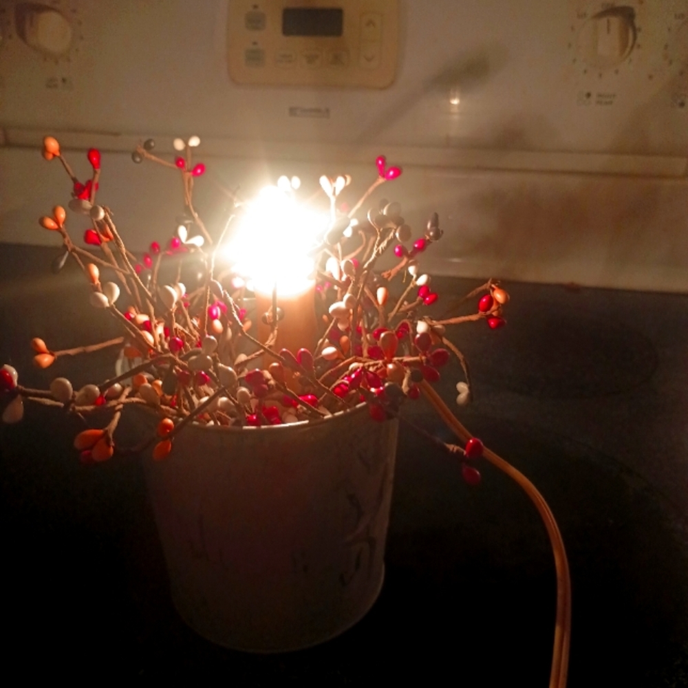 Primitive decor tin with pip berries and a candle in the middle of it